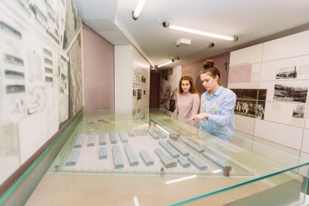 Besucherinnen schauen sich die Vitrinen in der Ausstellung an